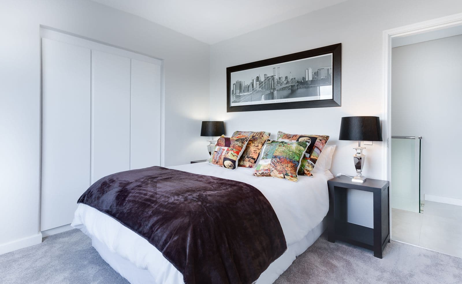 Bedroom with clean white walls and a dark throw blanket