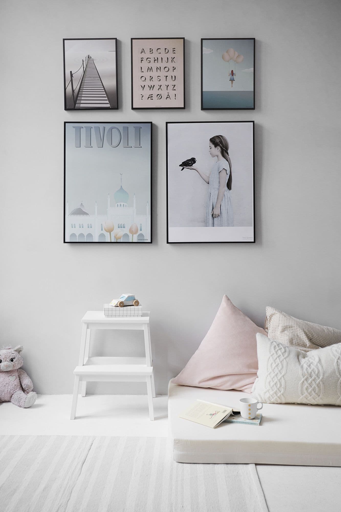 Soft gray wall with a framed gallery of prints above a reading corner